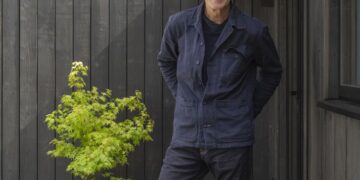 Kevin McCloud stands outside a dark timber home in Grand Designs UK season 24.