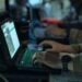 People using laptops in a military-style setting for Four Corners Click to Kill The AI War Machine