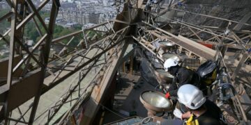 Workers on the Eiffel Tower appear high above Paris in Eiffel Tower: Life Behind The Scenes.