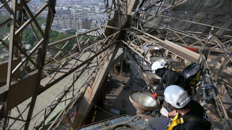 Workers on the Eiffel Tower appear high above Paris in Eiffel Tower: Life Behind The Scenes.