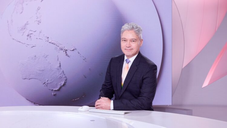 Anton Enus seated at the SBS World News desk