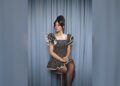 Lily Allen seated in front of blue curtains