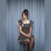 Lily Allen seated in front of blue curtains