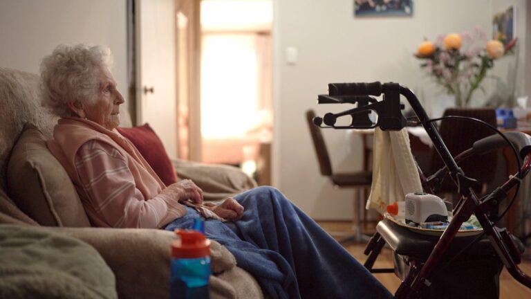 An older woman seated at home in Four Corners: The Waiting Game on ABC