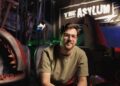 Mockbuster director Anthony Frith on a creature-film set beneath The Asylum sign