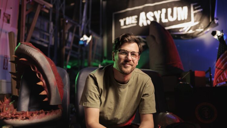 Mockbuster director Anthony Frith on a creature-film set beneath The Asylum sign