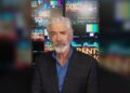Shaun Micallef in front of studio screens promoting Parents' Evening