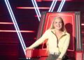 Tones And I seated in a red coach chair on The Voice