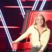 Tones And I seated in a red coach chair on The Voice