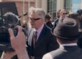 Alec Baldwin surrounded by cameras outside a courthouse