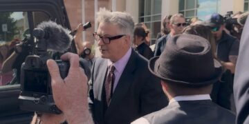 Alec Baldwin surrounded by cameras outside a courthouse