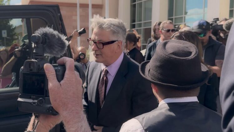 Alec Baldwin surrounded by cameras outside a courthouse