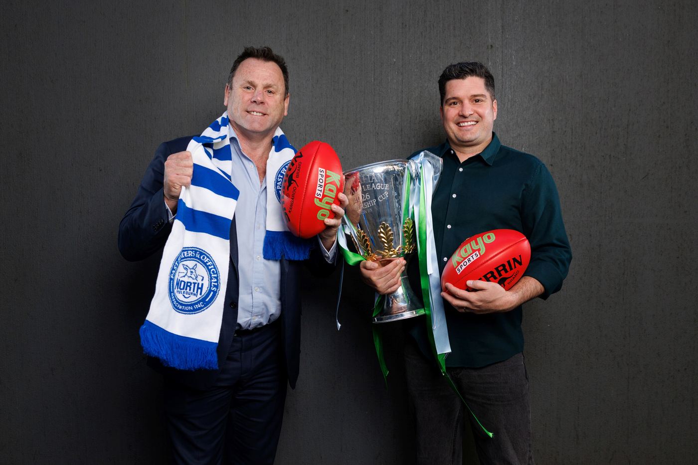 David King and Leigh Montagna hold footballs alongside the AFL premiership cup ahead of Grand Final week.