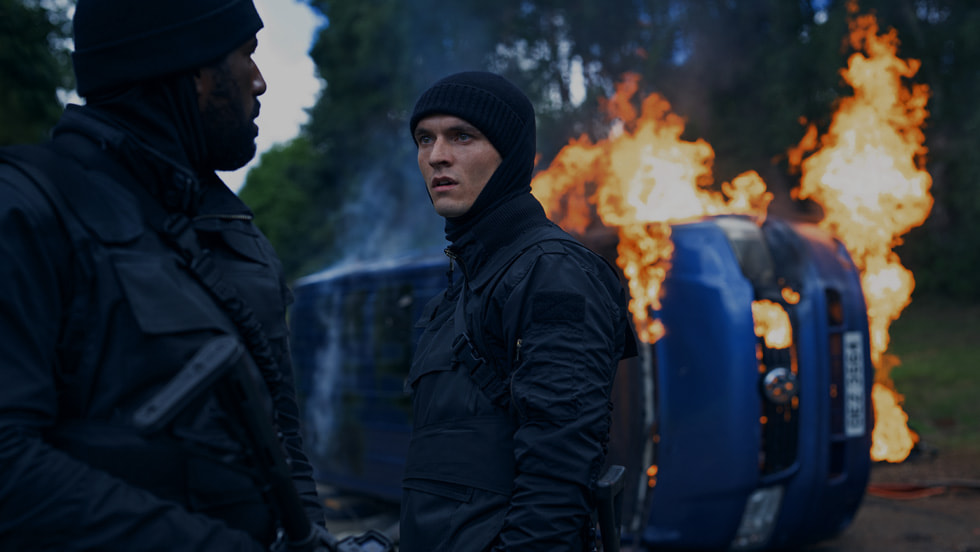 Fionn Whitehead beside a burning vehicle in The Wanted Man