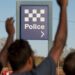 Community members raise their hands near a Northern Territory police sign in 2.6 Seconds: Death in the Outback