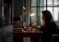 A woman works at a desk by lamplight in Believe in Magic: The Mother of All Cons on ABC
