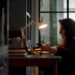 A woman works at a desk by lamplight in Believe in Magic: The Mother of All Cons on ABC