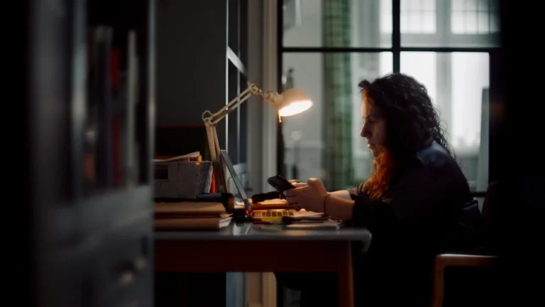 A woman works at a desk by lamplight in Believe in Magic: The Mother of All Cons on ABC
