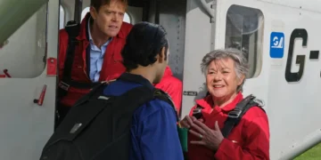 Characters in skydiving gear beside a plane in Beyond Paradise on ABC