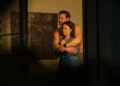 Two characters embrace in a dimly lit room in Dustfall on ABC