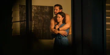 Two characters embrace in a dimly lit room in Dustfall on ABC