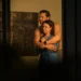 Two characters embrace in a dimly lit room in Dustfall on ABC