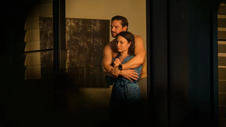 Two characters embrace in a dimly lit room in Dustfall on ABC
