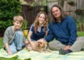 Two children and a presenter on a picnic rug with a dog in Gardening Australia Junior on ABC Kids