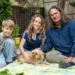 Two children and a presenter on a picnic rug with a dog in Gardening Australia Junior on ABC Kids