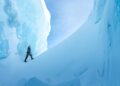 An explorer walks between towering blue ice formations in Ages of Ice