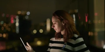 A woman looking at a glowing phone in AI Confidential with Hannah Fry