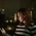 A woman looking at a glowing phone in AI Confidential with Hannah Fry