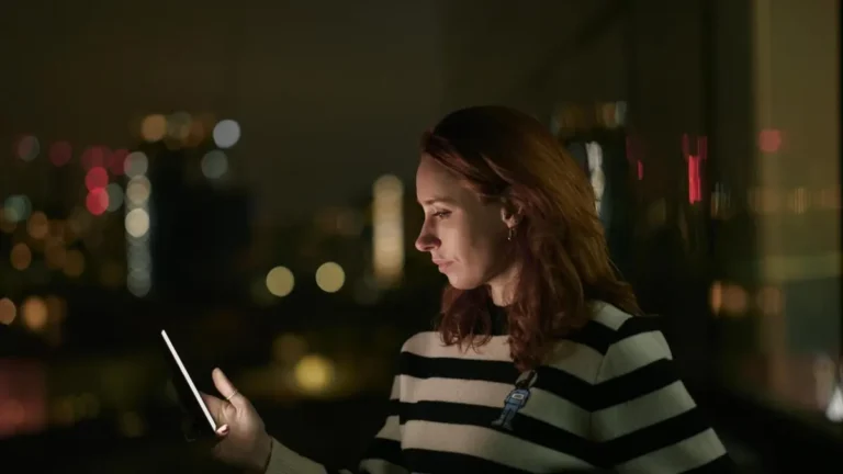 A woman looking at a glowing phone in AI Confidential with Hannah Fry