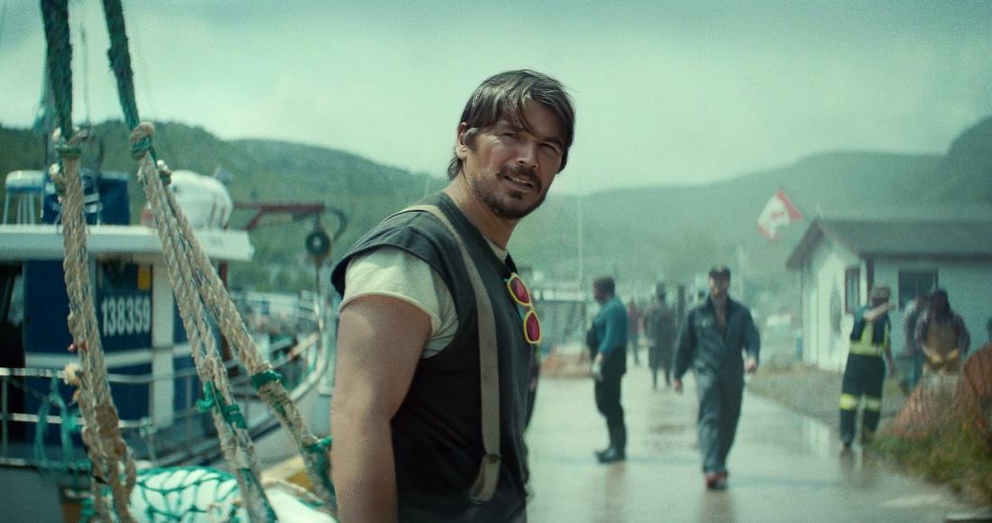 Josh Hartnett standing by a harbour in Below