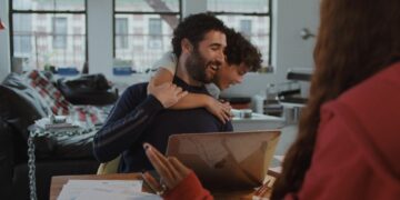 Jordan Firstman laughs as Reggie Absolom hugs him from behind in Club Kid