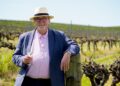 News24 Wine and Travel Editor Des Houghton holding a glass of white wine in a vineyard
