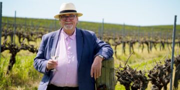 News24 Wine and Travel Editor Des Houghton holding a glass of white wine in a vineyard