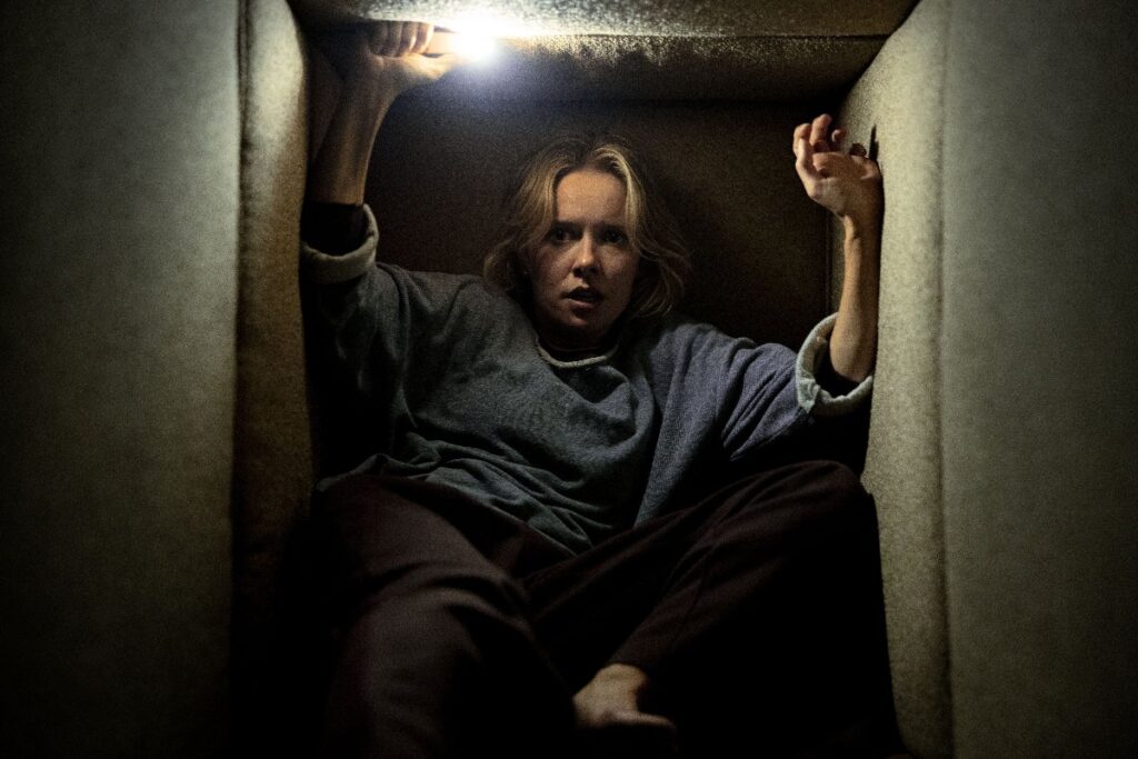 A frightened woman in a dark crawlspace in Insidious: Out of the Further