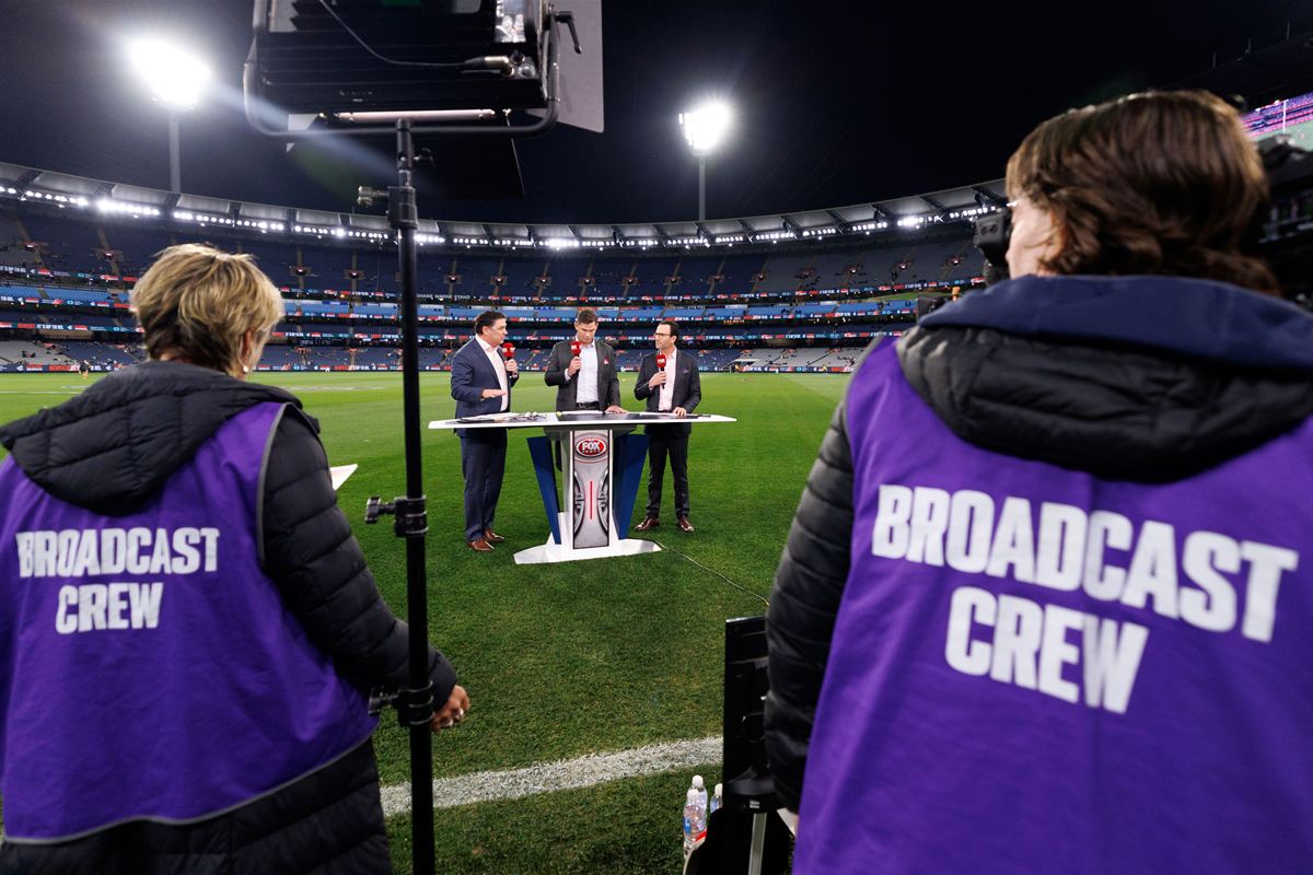 A Kayo Sports football broadcast team working beside the field at the MCG.