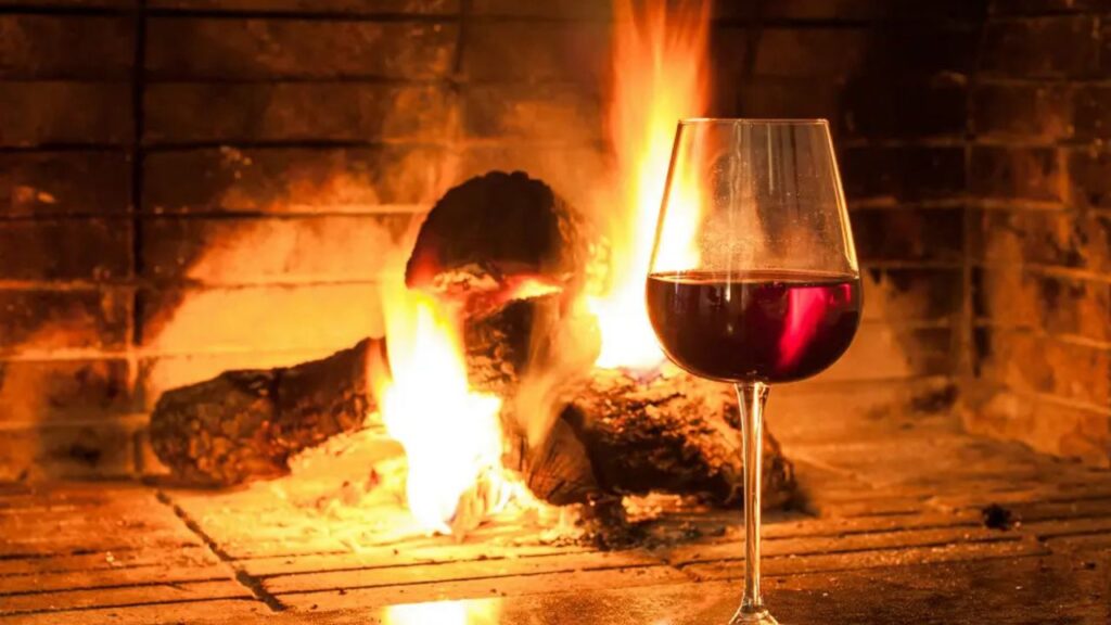 A glass of red wine beside an open fire, from the News24 Wine Club