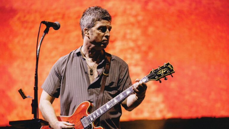 Noel Gallagher playing guitar during the Oasis reunion tour
