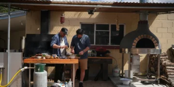 Colin Fassnidge and Manu Feildel prepare food at an outdoor kitchen