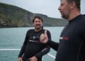 Colin Fassnidge and Manu Feildel in wetsuits on a boat in Akaroa for Off the Grid with Colin and Manu