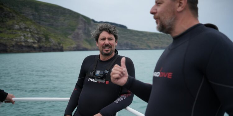 Colin Fassnidge and Manu Feildel in wetsuits on a boat in Akaroa for Off the Grid with Colin and Manu