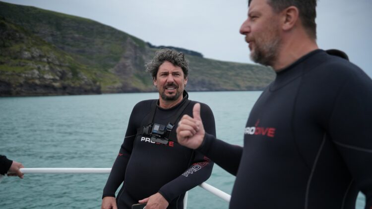 Colin Fassnidge and Manu Feildel in wetsuits on a boat in Akaroa for Off the Grid with Colin and Manu
