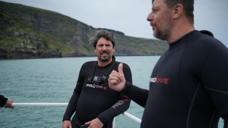Colin Fassnidge and Manu Feildel in wetsuits on a boat in Akaroa for Off the Grid with Colin and Manu