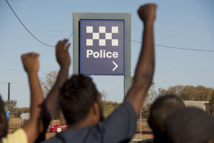 People raise their fists near a police station in 2.6 Seconds: Death in the Outback