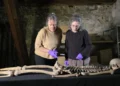 Two researchers examine an ancient skeleton laid out on a table