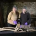 Two researchers examine an ancient skeleton laid out on a table