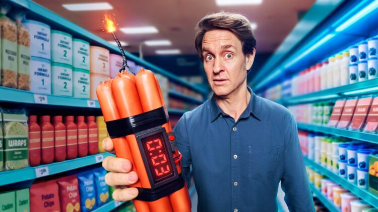 Craig Reucassel holds a bundle of sausages rigged like a bomb in a supermarket aisle for The Great Food Con on ABC